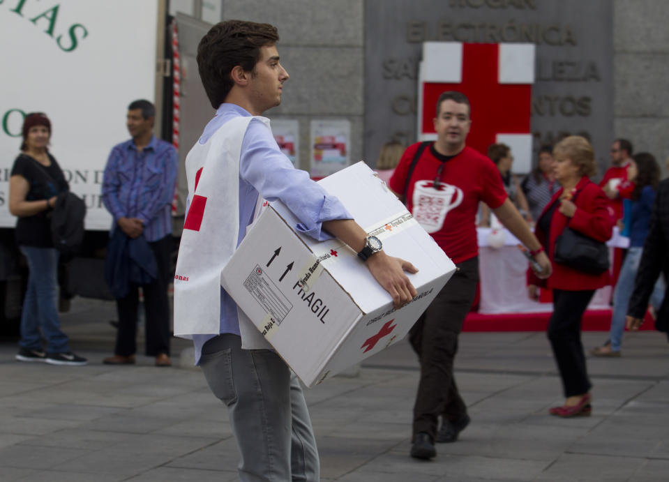 A Red Cross worker carries a box in Madrid, Wednesday Oct. 10, 2012. Spain’s Red Cross is launching its first-ever public appeal for donations to help the growing number of Spaniards in need of help because of the economic crisis. Spokesman Miguel Angel Rodriguez said Tuesday the agency is looking to round up some euro 30 million ($38.87 million) over the next two years to help an extra 300,000 people. (AP Photo/Paul White)