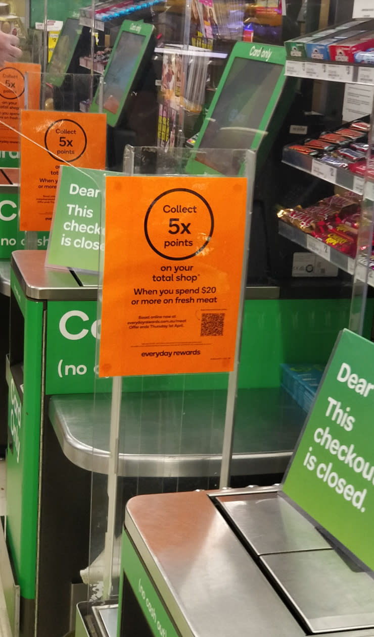 A promotional sign at Woolworths offering Rewards points for fresh meat purchases.