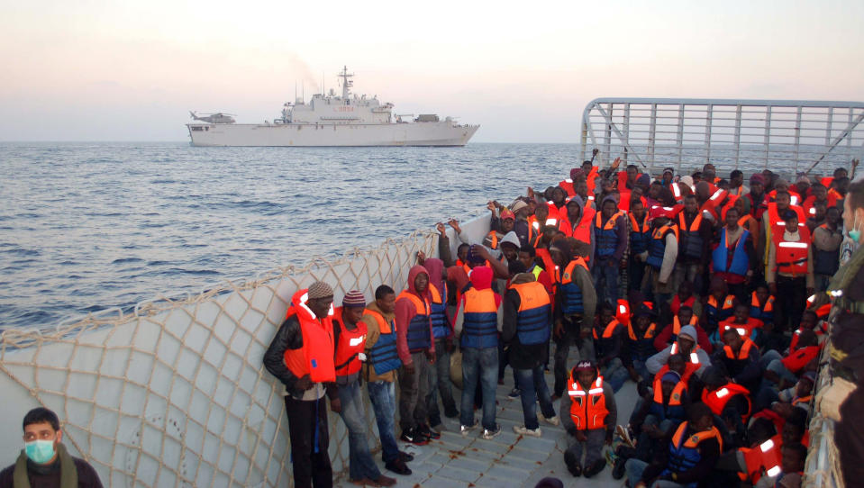 In this photo released by the Italian Navy Thursday, March 20, 2014, rescued migrants are about to be boarded on the San Giusto ship, background, along the Mediterranean sea. Italian authorities say they have rescued more than 4,000 would-be migrants at sea over the past four days as the war in Syria and instability in Libya spawn new waves of refugees. The numbers of migrants reaching Italian shores generally rises as warm weather and calm seas make the Mediterranean Sea crossing from North Africa easier. But the U.N. refugee agency says the 2014 numbers represent a 300 percent increase over the same period in 2013. (AP Photo/Italian Coast guard)