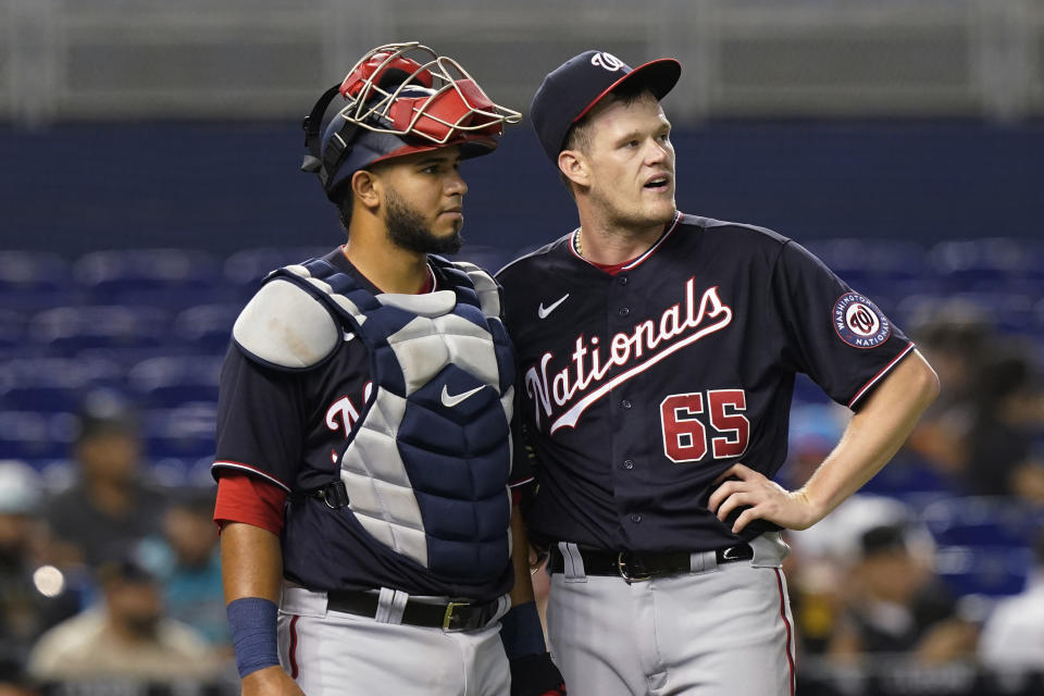 Washington Nationals' catcher Keibert Ruiz and pitcher Josh Rogers (65) watch the replay of a hit by Miami Marlins' Miguel Rojas during the third inning of a baseball game against the Miami Marlins, Tuesday, Sept. 21, 2021, in Miami. (AP Photo/Marta Lavandier)