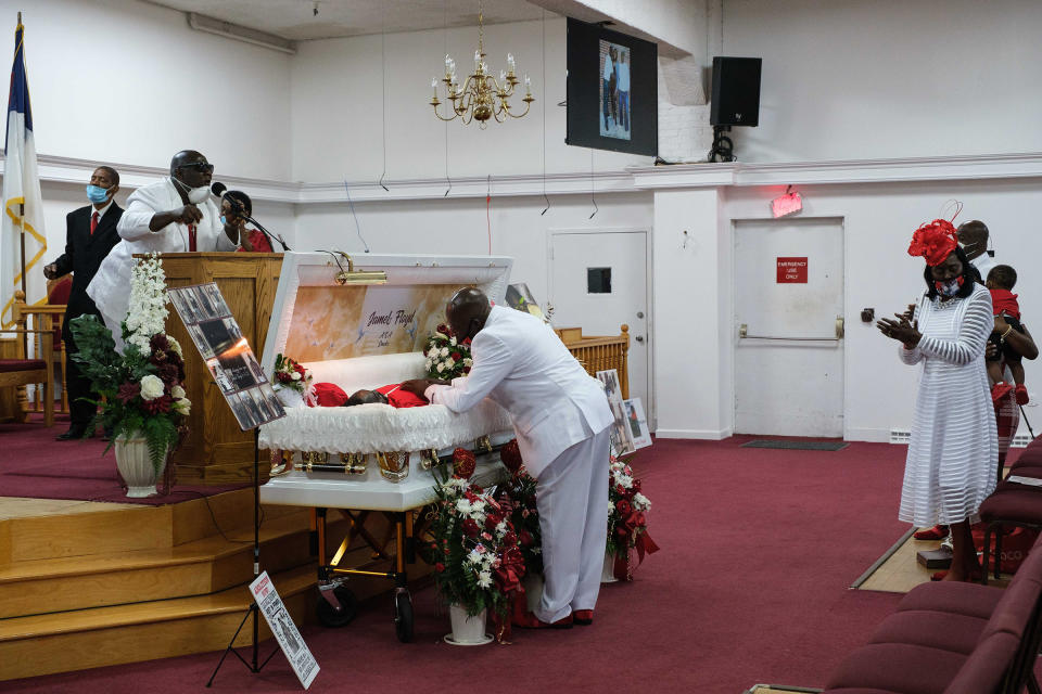 James Floyd stands over his son's body while community members sing.<span class="copyright">Yuki Iwamura</span>