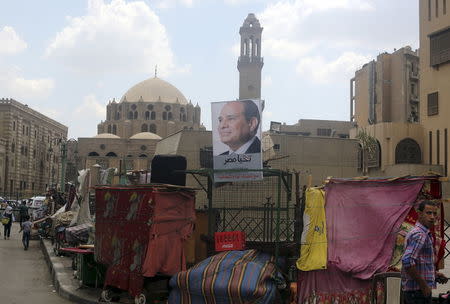 A poster of Egypt's then-presidential candidate, former army chief Abdel Fattah al-Sisi, is seen at a stall, with the Al-Azhar Mosque in the background, in the old Islamic area of Cairo, Egypt in this May 8, 2014 file photo. REUTERS/Amr Abdallah Dalsh/Files