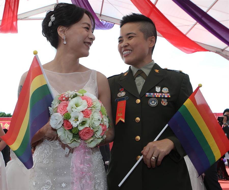 同志佳偶的王翊少校（右）與太太孟酉玫（左）帶著彩虹旗進場接受親友的祝福。(陳怡誠攝)