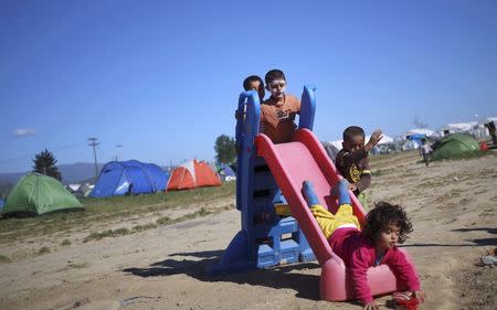 Children play on a slide at a makeshift camp for refugees and migrants at the Greek-Macedonian border near the village of Idomeni, Greece, April 15, 2016. REUTERS/Stoyan Nenov