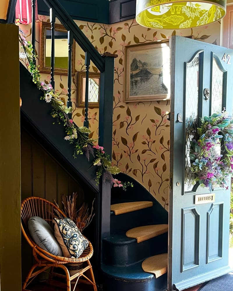 Floral wallpaper leading up stairs in entry of home.