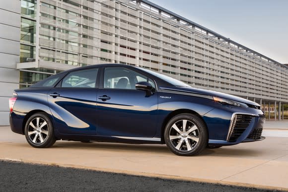 A dark blue Toyota Mirai sedan outside an office building.