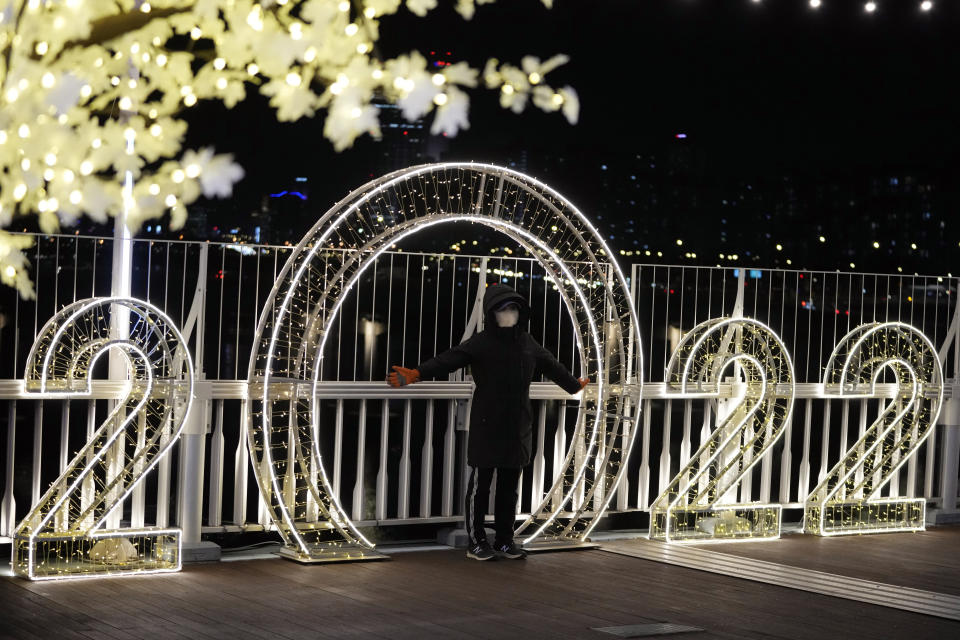 A visitor wearing a face mask poses for a photo in front of an illuminated decorations on New Year's Eve in Seoul, South Korea, Friday, Dec. 31, 2021. (AP Photo/Lee Jin-man)