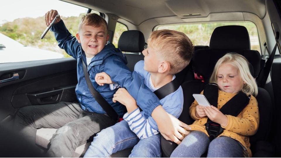 Hermanos peleando en el auto.