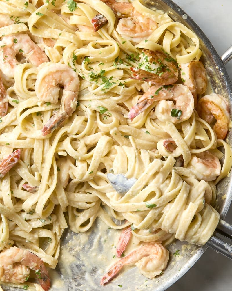 overhead shot of shrimp pasta in a pan, with some taken out of it.