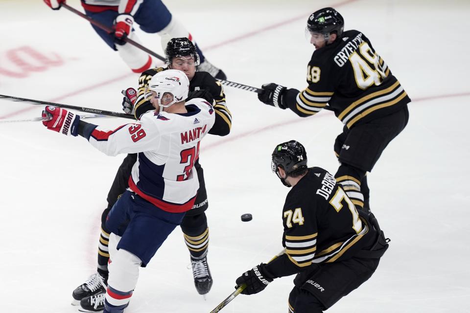 Boston Bruins' Charlie McAvoy (73) checks Washington Capitals' Anthony Mantha (39) in front of Jake DeBrusk (74) and Matt Grzelcyk (48) during the first period of an NHL hockey game, Saturday, Feb. 10, 2024, in Boston. (AP Photo/Michael Dwyer)