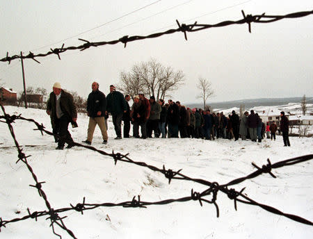FILE PHOTO: Ethnic Albanian villagers form a line to pay their respects to the family of two victims of an outbreak of ethnic violence, in Kosovo January 31, 1999. REUTERS/Yannis Behrakis/File photo