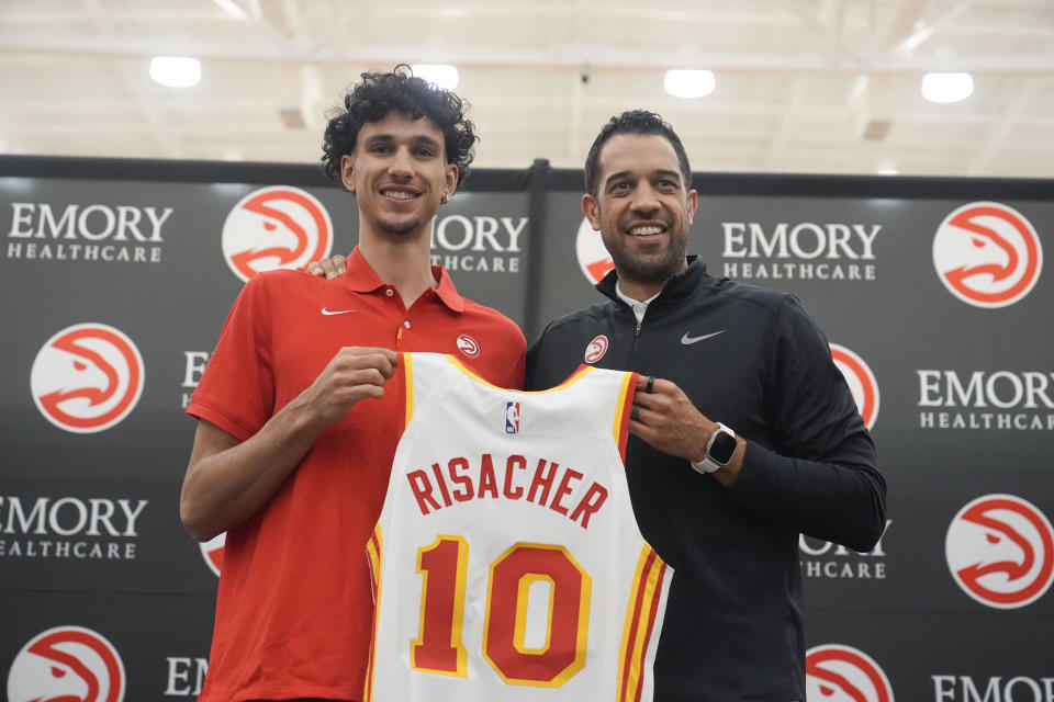 Atlanta Hawks' Zaccharie Risacher, left, and General Manager Landry Fields, right, hold up Risacher's jersey after an NBA basketball news conference, Friday, June 28, 2024, in Atlanta. Risacher was selected as the first overall pick by the Atlanta Hawks in the first round of the NBA basketball draft. (AP Photo/Brynn Anderson)