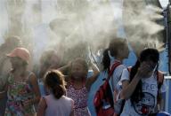 Children cool off in front of misting fans at the Australian Open 2014 tennis tournament in Melbourne January 15, 2014. REUTERS/Jason Reed