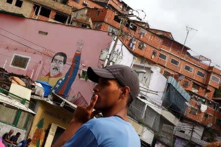 A local resident waits for a bus at next to a graffiti of Venezuela's President Nicolas Maduro at Jose Felix Ribas neighborhood in Caracas, Venezuela January 30, 2019. REUTERS/Carlos Barria