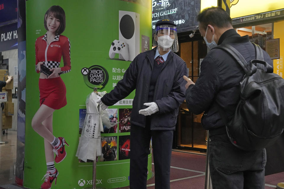 A worker wearing face mask, asks a man to scan the government's contact tracing QR code for the "LeaveHomeSafe" COVID-19 mobile app at an entrance of a shopping mall in Hong Kong, Thursday, Feb. 17, 2022. Hong Kong on Thursday reported 6,116 new coronavirus infections, as the city’s hospitals reached 90% capacity and quarantine facilities are at their limit, authorities said. (AP Photo/Kin Cheung)