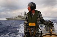 An Australian Navy sailor looks for debris on a rigid inflatable boat as HMAS Perth searches for missing Malaysia Airlines flight MH 370 in the southern Indian Ocean, April 13, 2014
