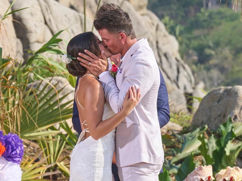 Mari Pepin, in a white backless wedding gown, kisses Kenny Braasch, in a white suit, during their wedding ceremony on "Bachelor in Paradise" season 9.