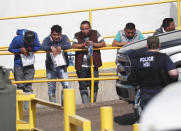 Handcuffed workers await transportation to a processing center following a raid by U.S. immigration officials at Koch Foods Inc., plant in Morton, Miss. U.S. immigration officials raided several Mississippi food processing plants on Wednesday and signaled that the early-morning strikes were part of a large-scale operation targeting owners as well as employees. (AP Photo/Rogelio V. Solis)