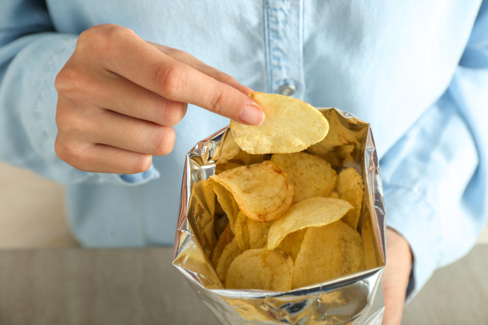 Woman eating tasty potato chips, closeup