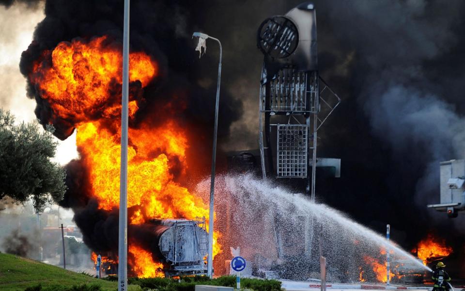 Israeli firefighters extinguish a fire that broke out after a suspected Hamas rocket hit a petrol station in the southern Israeli city of Ashdod - Reuters/Reuters