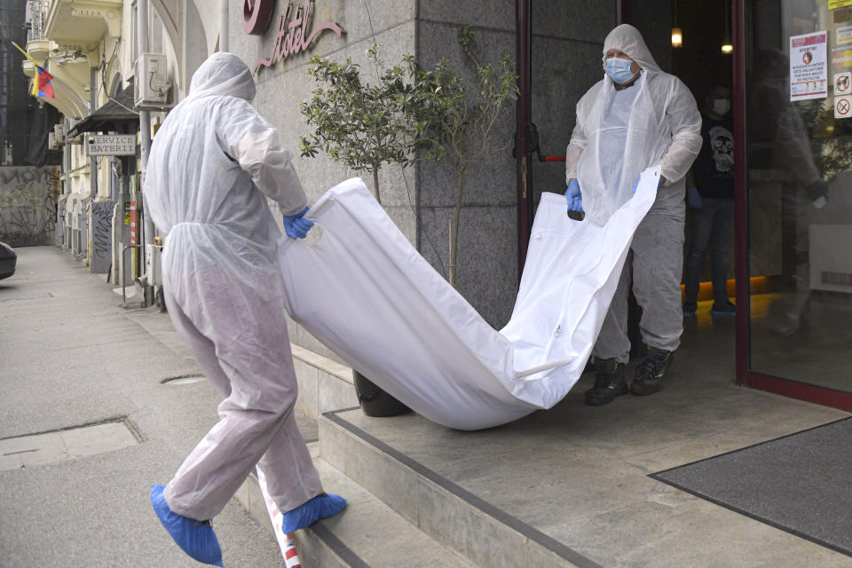 Forensic workers carry a body from a hotel downtown Bucharest, Romania, Friday, June 19, 2020. Gholamreza Mansouri, a former judge from Iran sought by his country to face corruption charges has died in unusual circumstances, Romanian media reported. Romanian police said only that a man had fallen from a high floor at a hotel in Bucharest, the Romanian capital, and was found dead. (AP Photo/Andreea Alexandru)