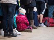 Es geht kein Zug nach Irgendwo: Ein kleines Mädchen sitzt am Kölner Hauptbahnhof zwischen Reisenden, die einen Informationsschalter belagern. Foto: Marius Becker