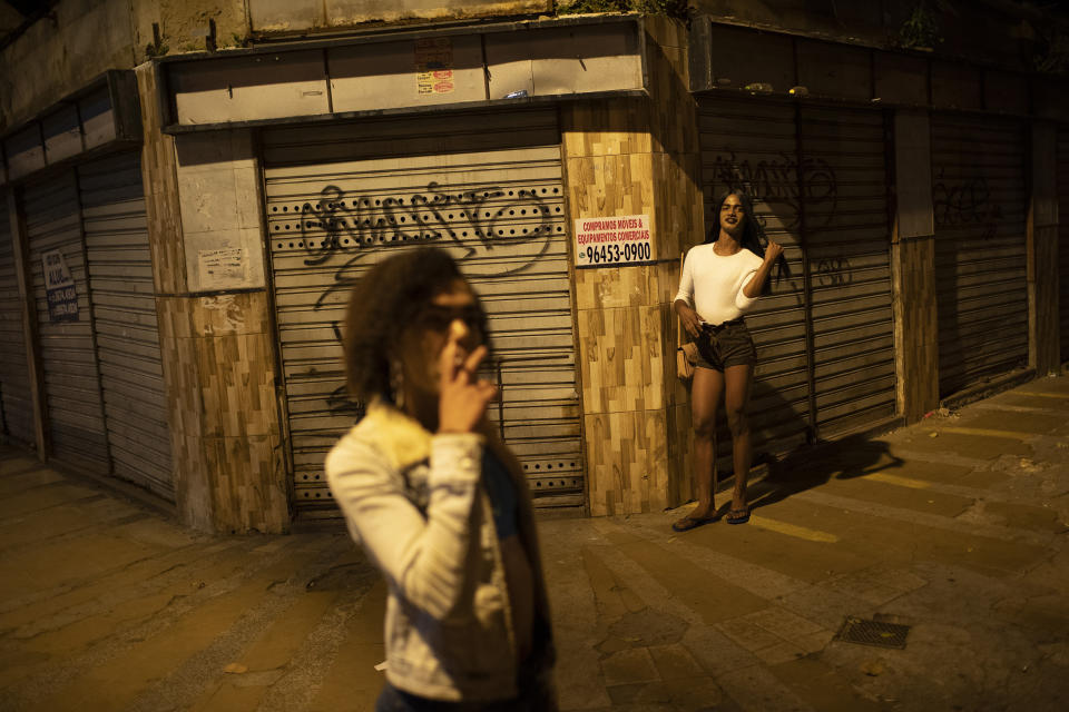 Transgender sex worker Alice Larubia smokes a cigarette as she waits for customers in Niteroi, Brazil, Saturday, June 27, 2020, amid the new coronavirus pandemic. After a month quarantining at home with some financial support from family, Larubia resumed work in Niteroi, a city across the bay from Rio. “Necessity spoke louder (than the pandemic) and I had to come back to the street,” Larubia said while waiting for clients with a small group of colleagues. (AP Photo/Silvia Izquierdo)