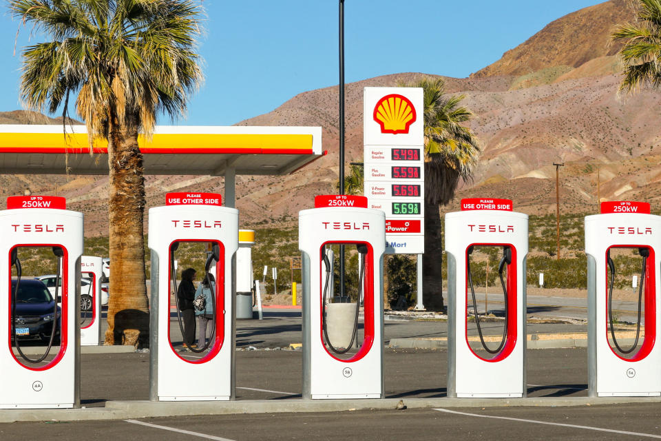 FILE PHOTO: A Tesla supercharger station is pictured next to a gas station in Yermo, California, U.S. February 12, 2024. REUTERS/Mike Blake/File Photo