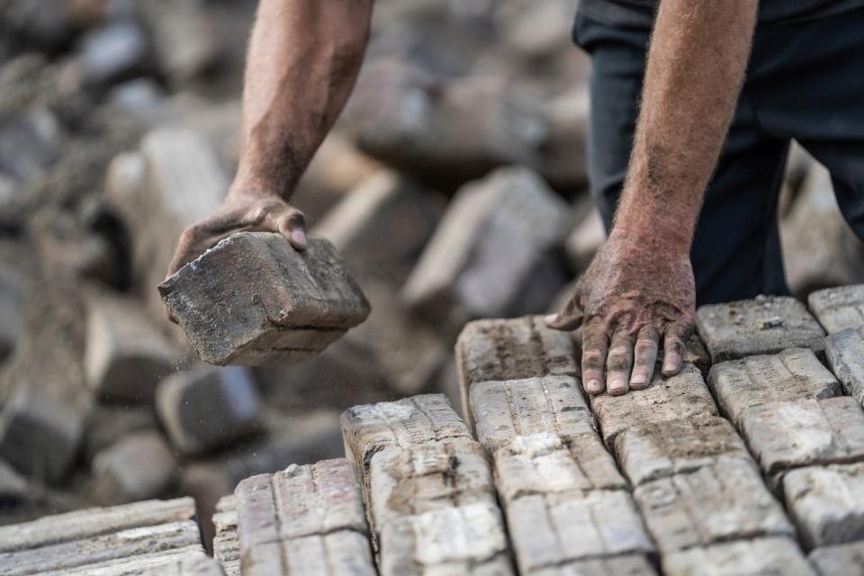 Jeff Cowin, of Detroit, works on stacking handmade Nelsonville block pavers donated by ITC and DTE to the city of Detroit to use for repairing Virginia Park Street in Detroit on Thursday, July 7, 2022, while loading a pallet at a lot along East Vernor Highway in Detroit.