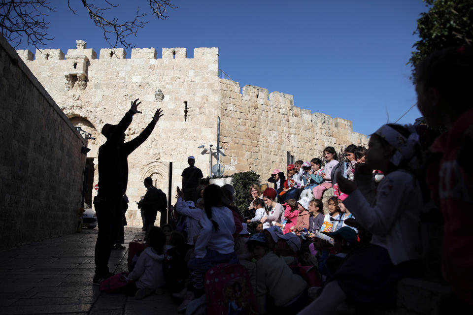 A man is silhouetted as he speaks to a group of children near Zion Gate in Jerusalem's Old City. (Photo: Nir Elias/Reuters)