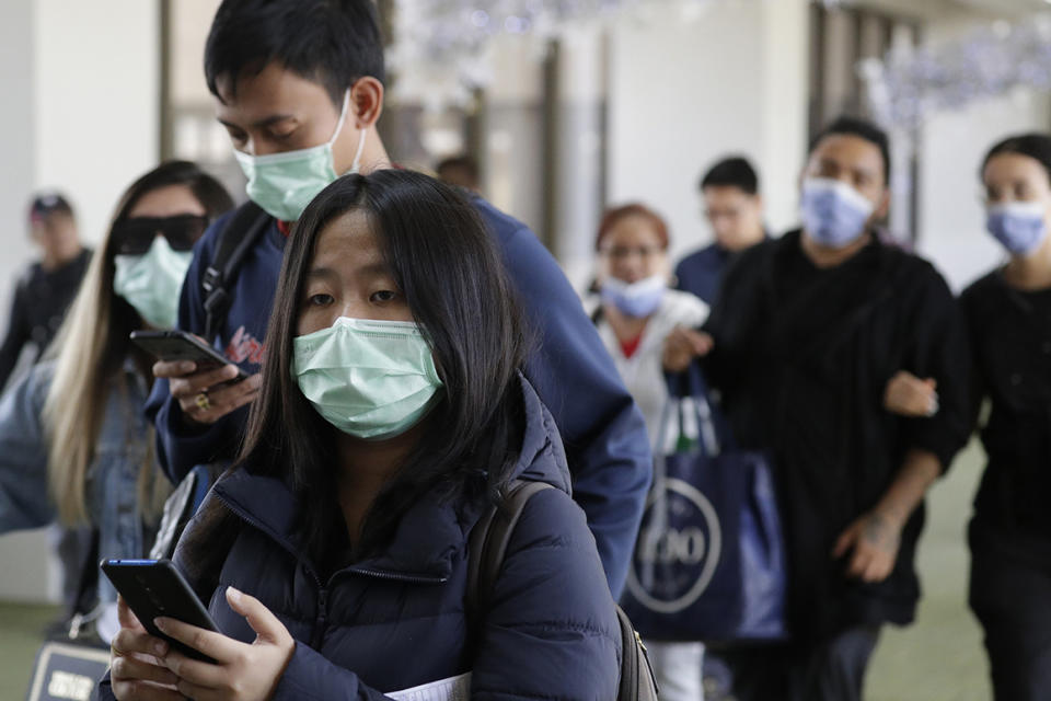 Passengers wear masks as they arrive at Manila's international airport, Philippines, Thursday, Jan. 23, 2020. The government is closely monitoring arrival of passengers as a new coronavirus outbreak in Wuhan, China has infected hundreds and caused deaths in that area. (AP Photo/Aaron Favila)