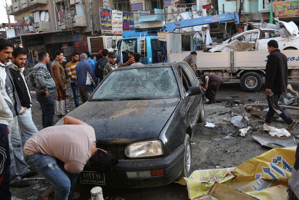 Civilians inspect the site of a car bomb attack at an outdoor market in Baghdad al-Jadidah district, Iraq, Monday, Jan. 20, 2014. A series of bombings in central Iraq killed dozens of people on Monday, as a government official claimed that al-Qaida-linked fighters have dug in to a city they seized last month and possess enough heavy weapons to storm into the country's capital. (AP Photo/Khalid Mohammed)