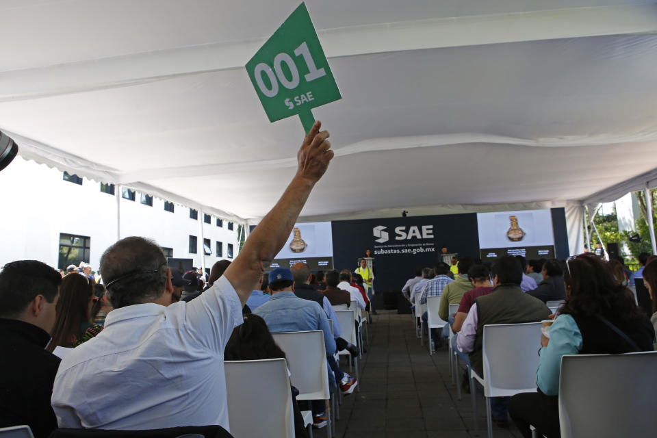 A man raises his paddle during an auction of government seized jewelry at Los Pinos Cultural Center, formerly the presidential residence, in Mexico City, Sunday, July 28, 2019. The auction was held by the Institute to Return the Stolen to the People, the name for a branch of the Finance Ministry charged with selling property seized from purported drug dealers and tax cheats, as well as government goods that are no longer in use. (AP Photo/Ginnette Riquelme)