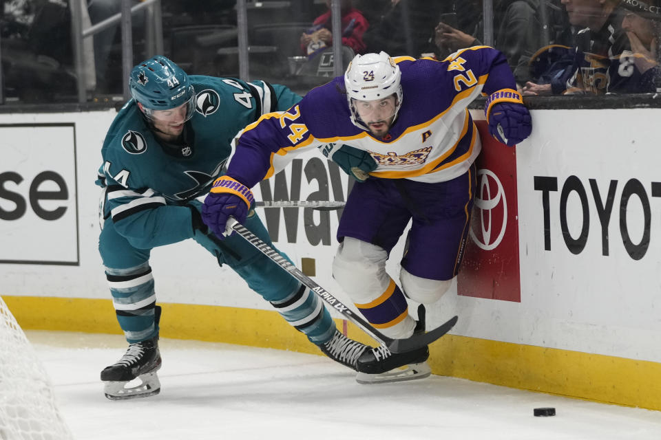 Los Angeles Kings' Phillip Danault (24) and San Jose Sharks' Marc-Edouard Vlasic (44) chase the puck during the second period of an NHL hockey game Saturday, Dec. 17, 2022, in Los Angeles. (AP Photo/Jae C. Hong)