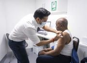 Pharmacist Bhaveen Patel administers a dose of the Oxford/AstraZeneca covid vaccine to Joshua Labor at a coronavirus vaccination clinic held at Junction Pharmacy in Brixton, London, Thursday, Jan. 28, 2021. (Dominic Lipinski/PA via AP)