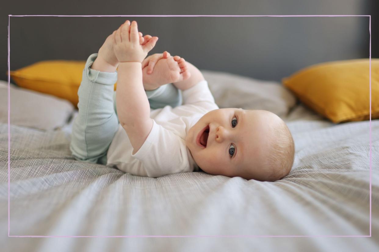  Baby rolling on bed with feet in hands. 