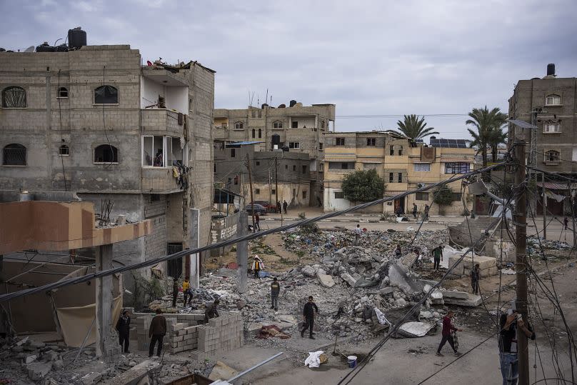 Palestinians inspect the rubble of the Hasouna family house, which was struck by an Israeli airstrike during an operation to rescue two hostages in Rafah, 13 February 2024