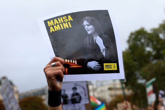 A protester shows a portrait of Mahsa Amini during a demonstration to support Iranian protesters standing up to their leadership over the death of a young woman in police custody in Paris