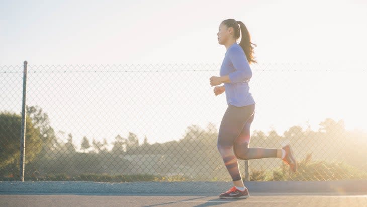 A women in a blue shirt is running around a track