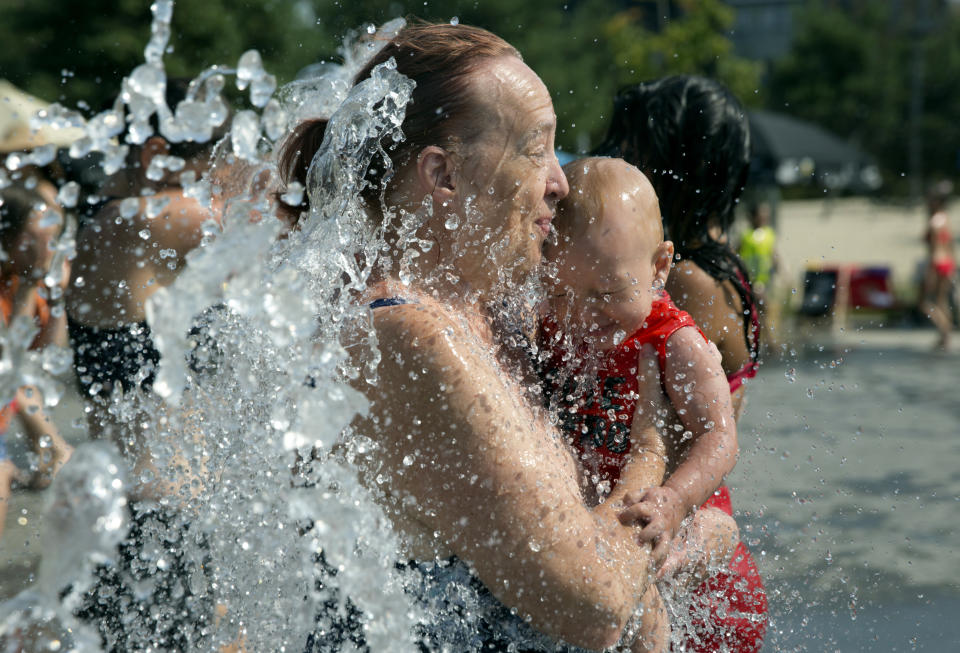 A mother and child cool off by walking through a park fountain in Antwerp, Belgium, Thursday, July 25, 2019. Belgium braced itself for code red, extreme heat warning, on Thursday as temperatures soared during the second heat wave of the summer. (AP Photo/Virginia Mayo)