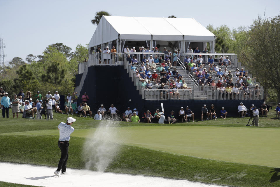 A small crowd watches Scottie Scheffler hit from the sand on the eighth hole, during the first round of The Players Championship golf tournament Thursday, March 12, 2020, in Ponte Vedra Beach, Fla. (AP Photo/Chris O'Meara)