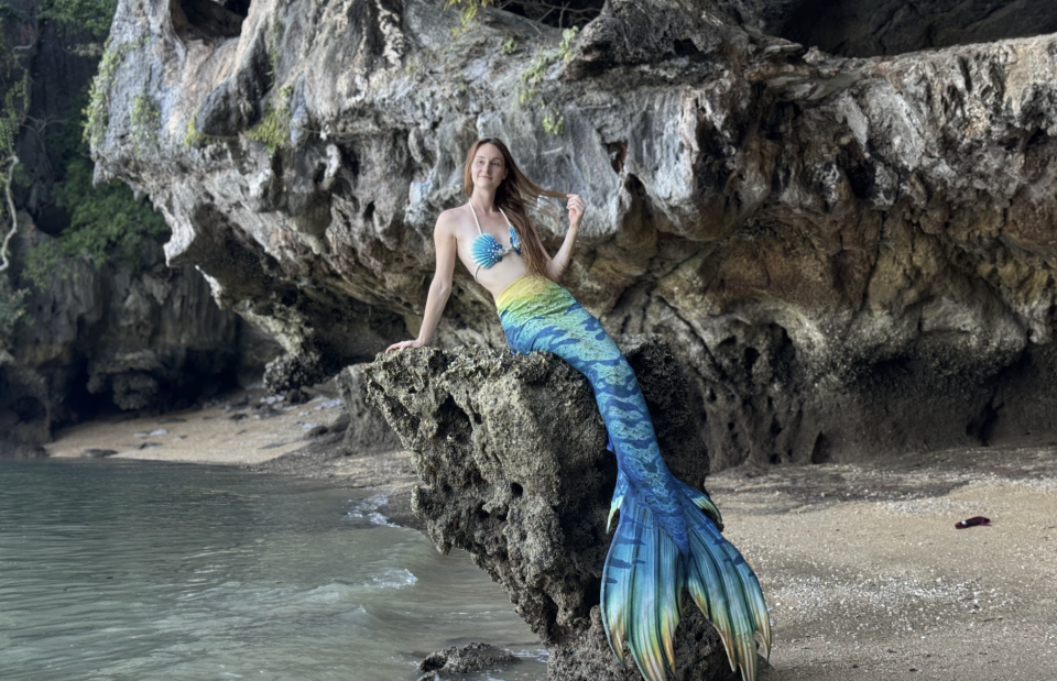 Marielle Henault, a professional mermaid, poses on a rock.  / Credit: Marielle Henault