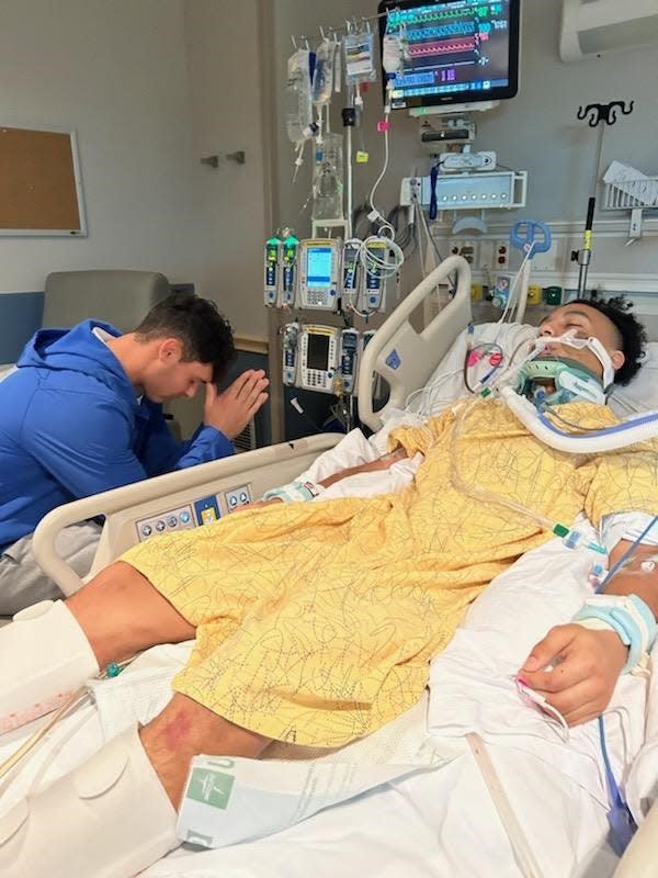 Senior teammate Alex Graber prays next to Will Jamison at Lutheran Hospital in Fort Wayne after Jamison's car accident on Nov. 18, 2023.