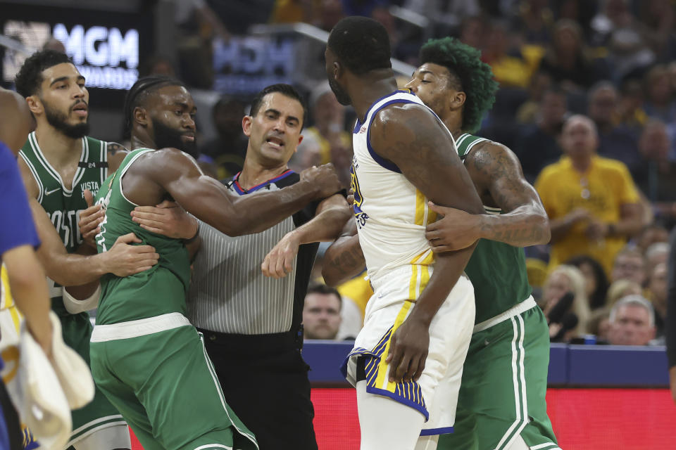 Boston Celtics guard Jaylen Brown, second from right, is held back by forward Jayson Tatum and referee Zach Zarba as Golden State Warriors forward Draymond Green, second from right, is held by Celtics guard Marcus Smart during the first half of Game 2 of basketball's NBA Finals in San Francisco, Sunday, June 5, 2022. (AP Photo/Jed Jacobsohn)