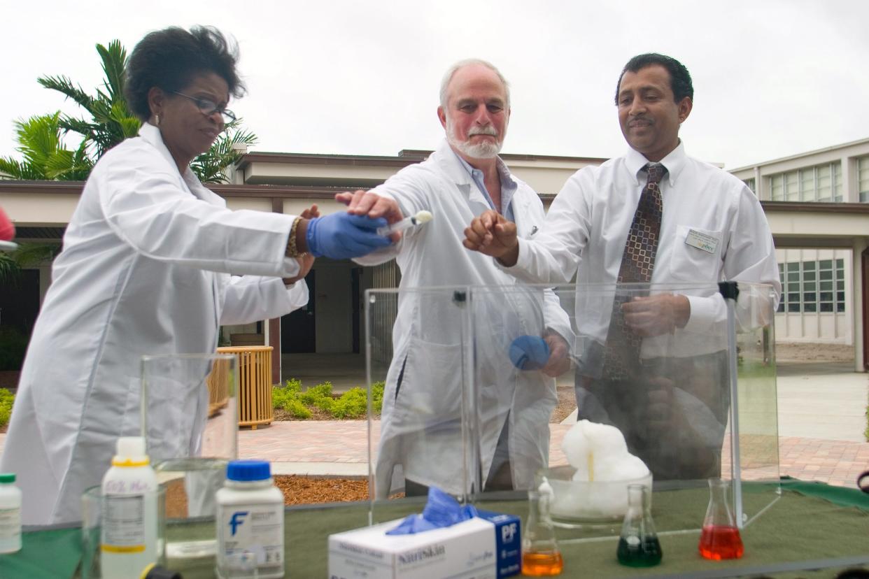 Carolyn Williams, a District Board of Trustees member, helps Peter Krieger, a chemistry professor, and Roger Ramsammy, then the interim dean of academic affairs,
during a chemical reaction demonstration to celebrate the 2008 opening of Palm Beach Community College's new Natural Science building in Lake Worth.
