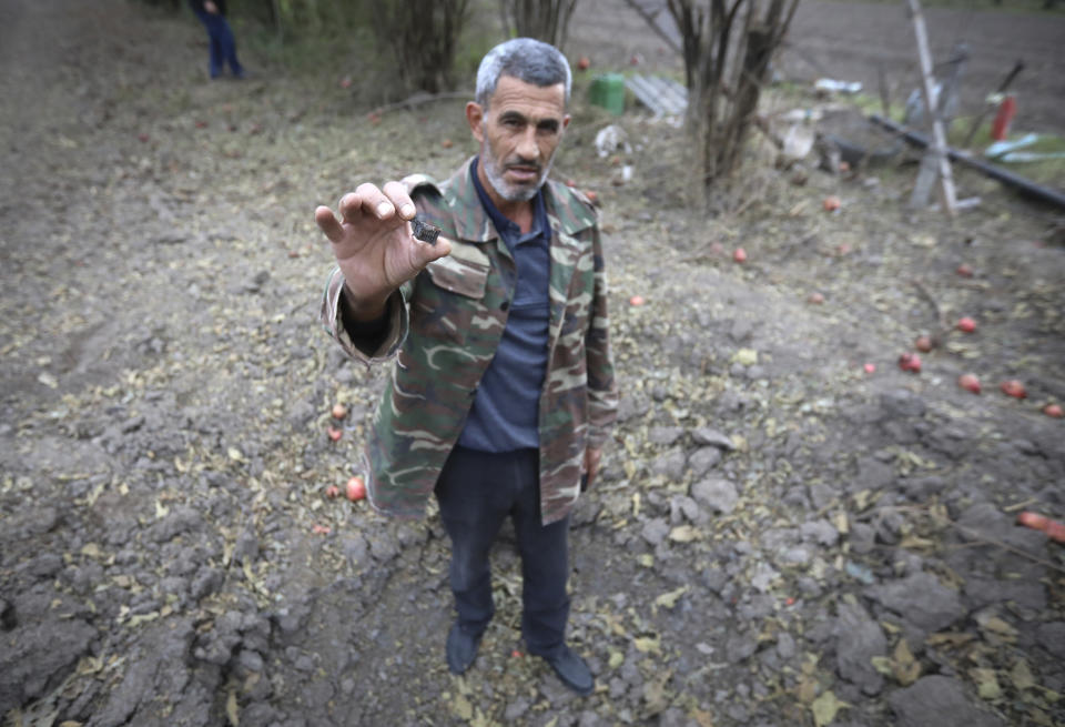 A man shows fragments of the projectile which he found at destroyed houses following a shelling during fighting over the breakaway region of Nagorno-Karabakh in Terter, Azerbaijan, Sunday, Oct. 4, 2020. The fighting between Armenian and Azerbaijani forces has continued on Sunday over the separatist territory of Nagorno-Karabakh, with Azerbaijan's second largest city coming under attack. Azerbaijani officials said Sunday that Armenian forces attacked the city of Ganja. (AP Photo/Aziz Karimov)