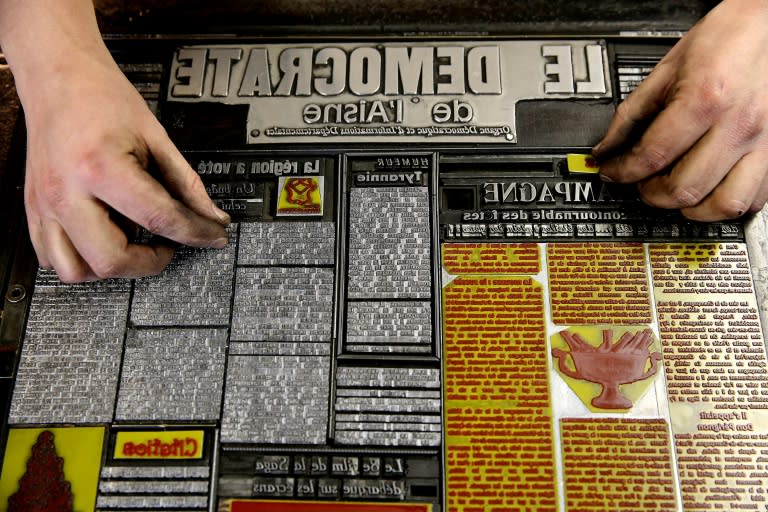 A worker adjusts lead slugs of type on a plaque in the composing room for the Democrate de l'Aisne