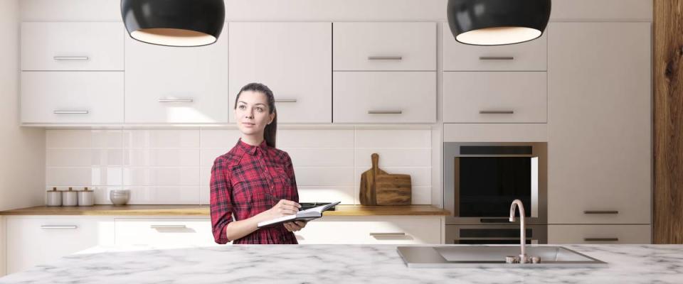 Woman in a white kitchen interior with large windows, a white marble table and a white marble countertop with a sink. 3d rendering