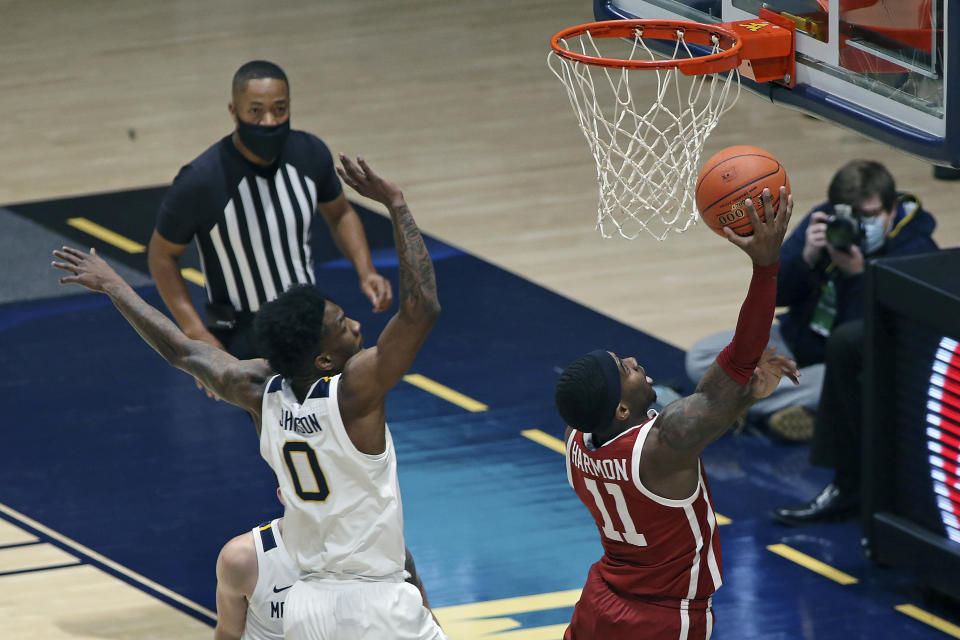 Oklahoma guard De'Vion Harmon (11) shoots past West Virginia guard Kedrian Johnson (0) during the first half of an NCAA college basketball game Saturday, Feb. 13, 2021, in Morgantown, W.Va. (AP Photo/Kathleen Batten)