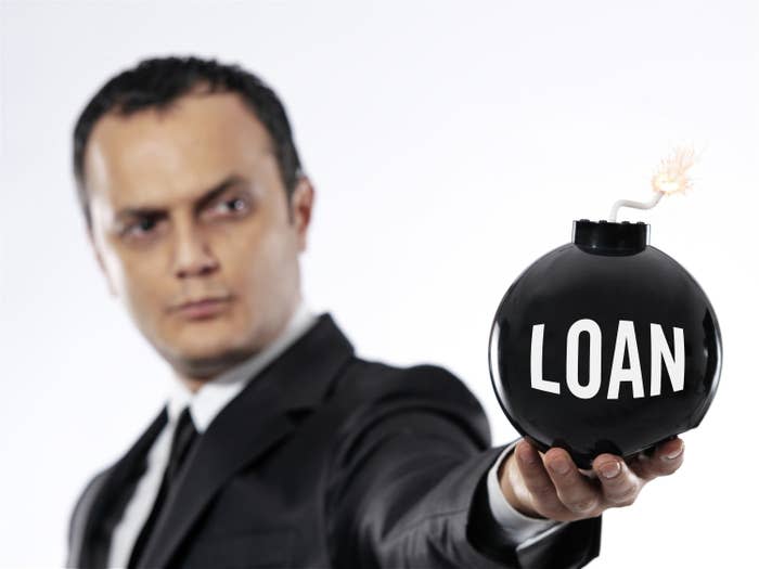 a man holding a fake bomb with the word &quot;loan&quot; on it